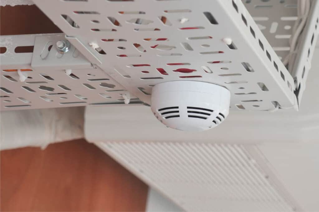 Commercial Electrician Perth WA fitting smoke detector in Maddington office